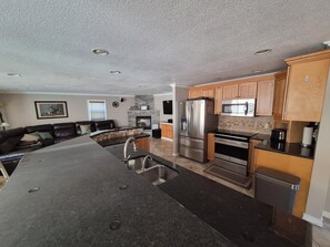 A modern kitchen with a central island, stainless steel appliances, and wooden cabinets.