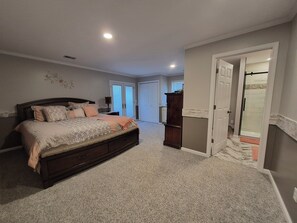 A bedroom with a large bed, a wardrobe, and a bathroom with a glass shower. - Stunning Lakefront house + guest house on beautiful Littlefield Lake (Lake)