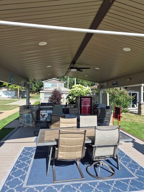 An outdoor patio with a covered seating area, a grill, and a stone fireplace.