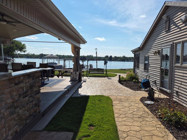 A patio area with outdoor seating, a view of a lake, and a house with a covered porch.