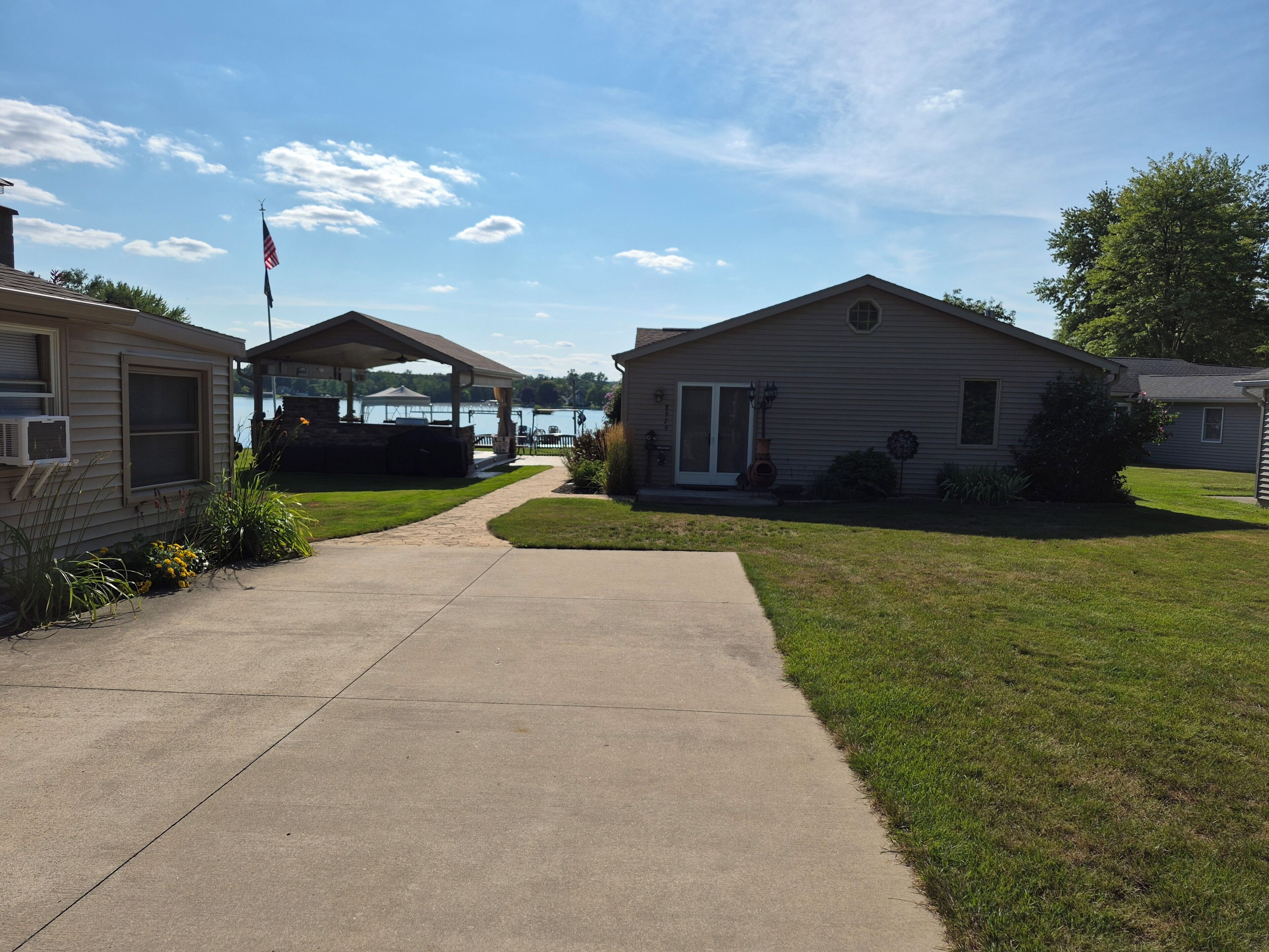 A residential area with a paved walkway leading to a covered patio area.