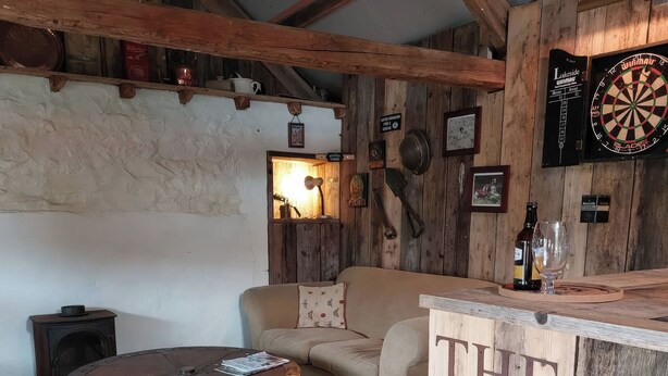 Un interior rústico con una mesa de madera, un sofá y un dardo.