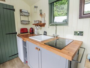 Una cocina compacta con un lavamanos, un tostador, una tetera y un refrigerador pequeño.
