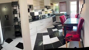A kitchen with a black and white checkered floor, white cabinets, and a red dining table with matching chairs. - Cozy 2-bedroom apartment in adorable Pančevo with AC (Pančevo)