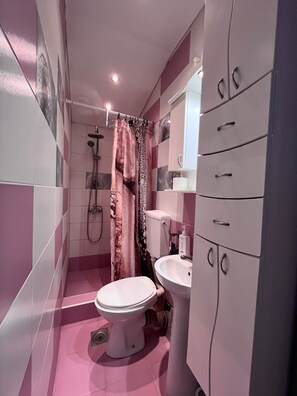 Un baño con inodoro, lavamanos, ducha y mueble de tocador.