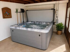 A hot tub in a room with white walls, a wooden plaque, a broom, and a potted plant. - Private Heated Pool • Hot Tub • Fenced Yard (Gahanna)