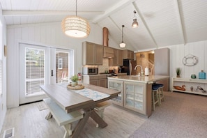 A kitchen with wooden cabinets, a central island, and pendant lighting. - Coastal cottage with hot tub, close walk to beach (Cannon Beach)