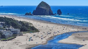 Una playa con tiendas de campaña, un río y formaciones rocosas a lo lejos.