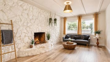 Ein Wohnzimmer mit Steinwand, Kamin, Sofa, Couchtisch und einer Pendelleuchte.