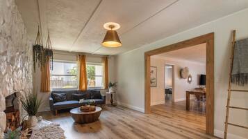 Ein geräumiges Wohnzimmer mit Holzboden, einem runden Couchtisch, einer Couch und einer Pendelleuchte.