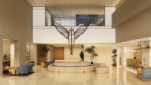 En rummelig lobby med et centralt siddeområde, et dekorativt loftelement og en receptionsdisk.