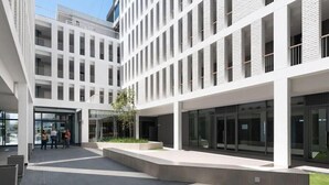 Un edificio moderno con un cortile interno, porte in vetro e un piccolo albero.
