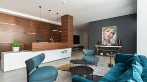Un'accoglienza moderna con una scrivania in legno, posti a sedere blu e un grande quadro appeso al muro.