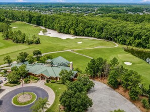 Ein Golfplatz mit Clubhaus, Kreisverkehr und See.
