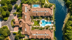 An aerial view of a resort with a swimming pool, multiple guest rooms, and a surrounding natural landscape. - The King & Bear Luxury Studio Retreat (St. Augustine)