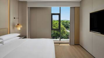 Una habitación de hotel moderna con una cama grande, televisión y ventana con vista a la ciudad.