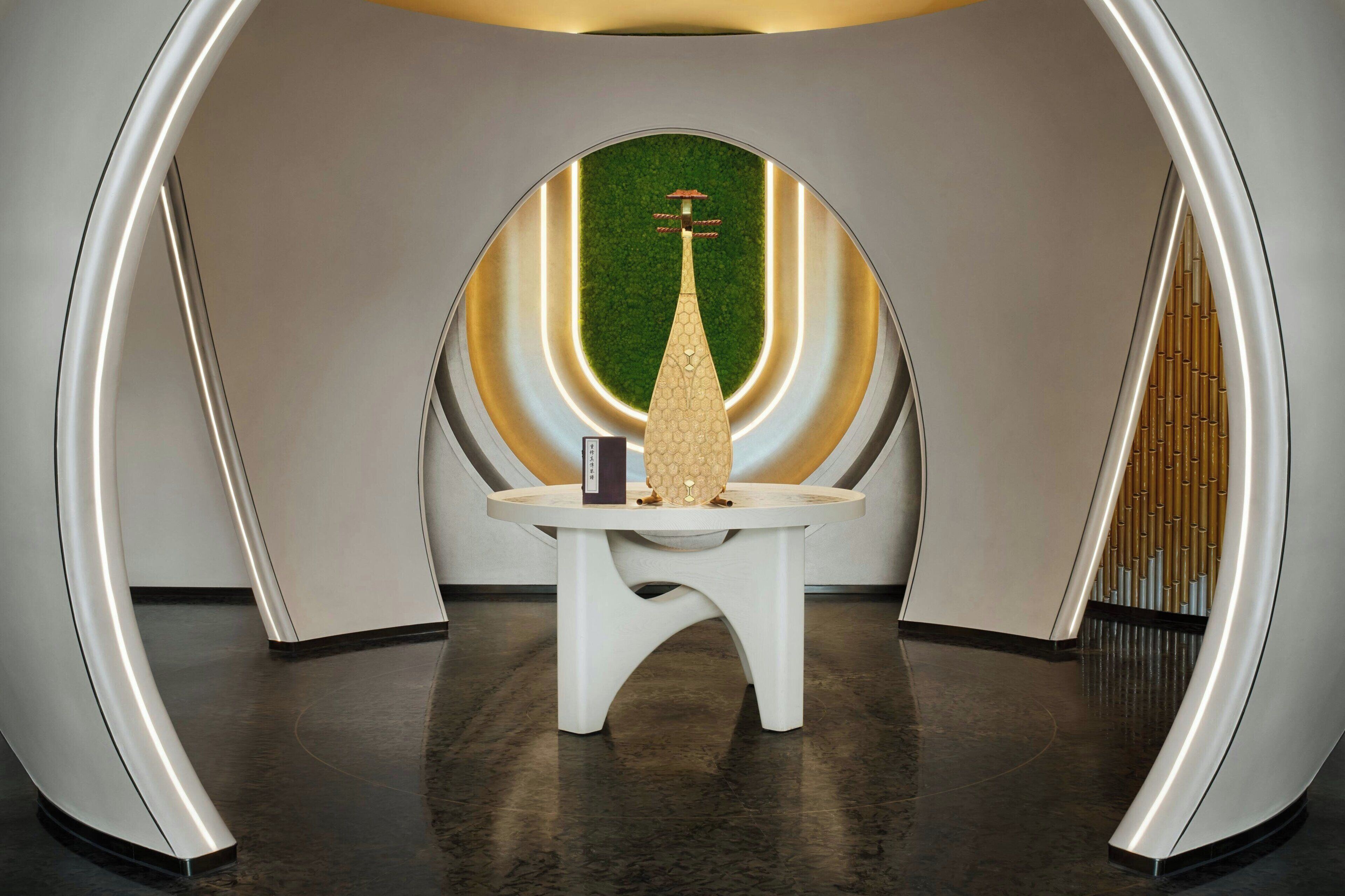 Una capilla moderna y minimalista con diseño geométrico, que presenta un altar central y una pared verde con textura.