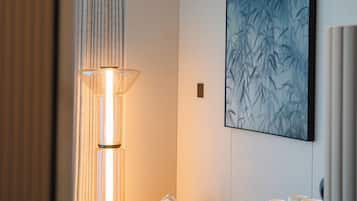 Ein modernes Hotelzimmer mit einer Couch, einer Stehlampe, einem Wandbild und einem Nachttisch mit Gegenständen.