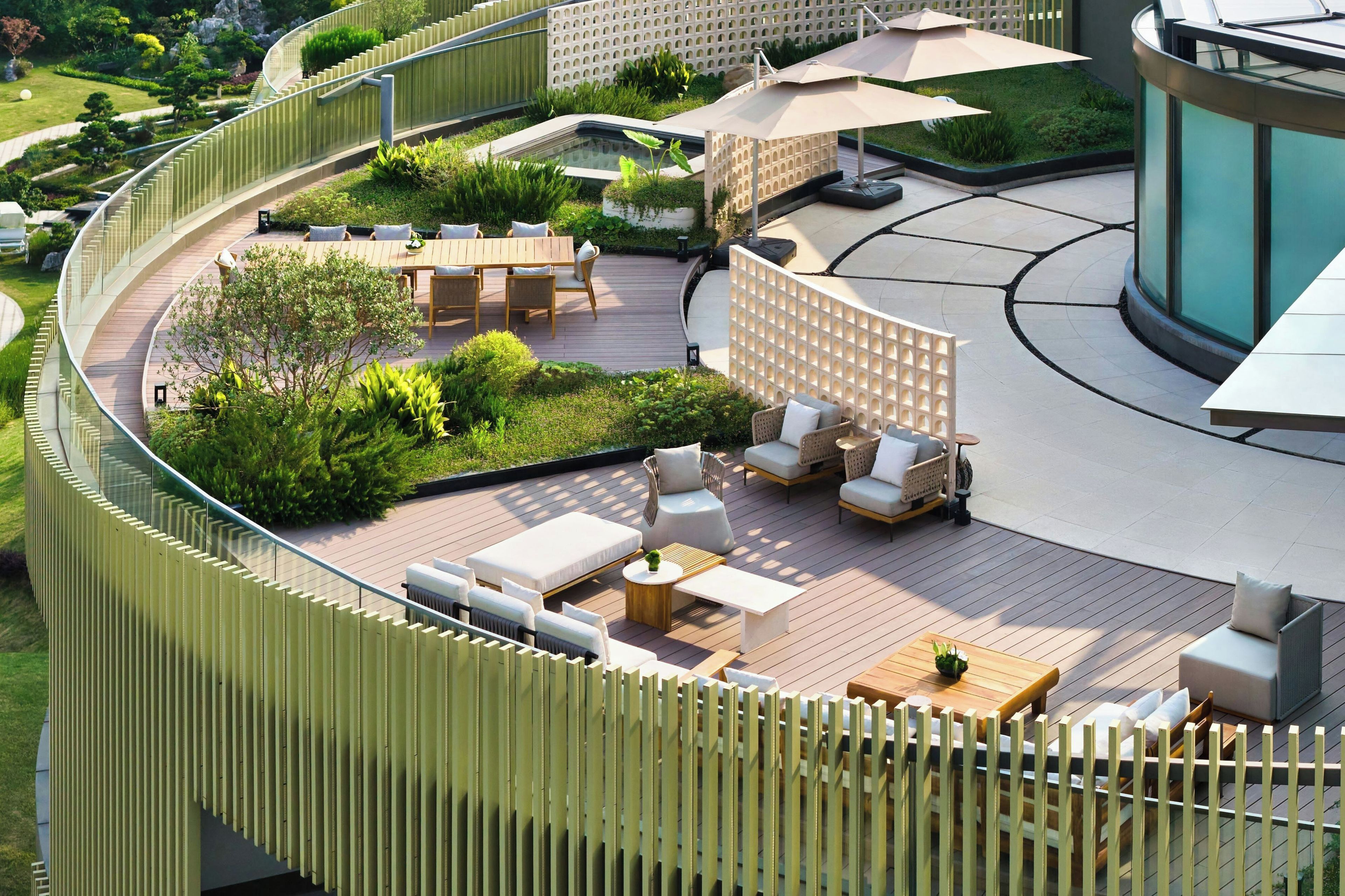 A modern outdoor patio area with a curved wooden deck, seating arrangements, and a pool.