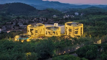 Un edifici modern amb disseny circular, envoltat de vegetació exuberànt i un paisatge amb turons.