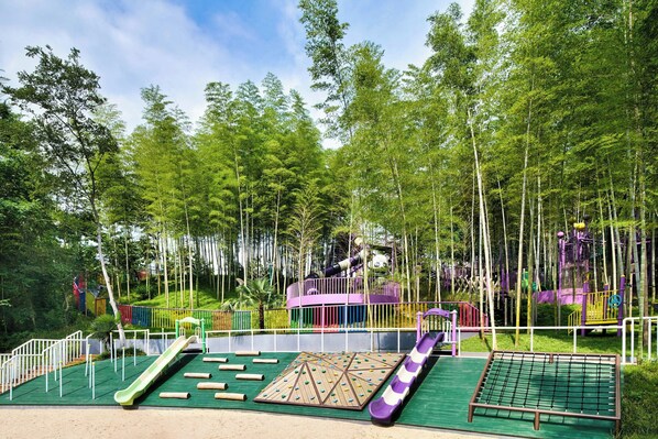 A playground with slides, climbing structures, and a netted area.