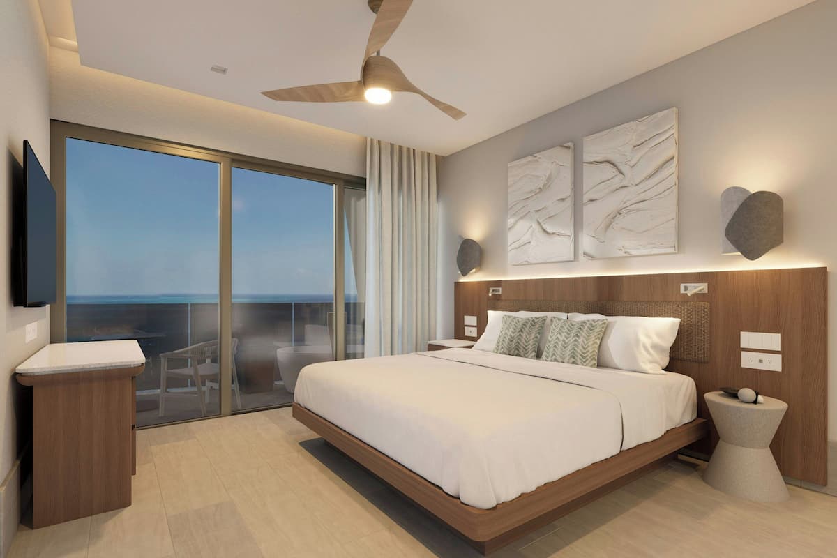 Une chambre moderne avec un grand lit, un ventilateur de plafond, une télévision et un balcon avec vue.