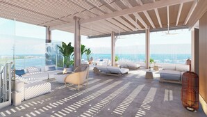 A modern outdoor lounge area with seating, a fire pit, and large windows offering a view of the ocean. - Casa Nizuc, A Tribute Portfolio Resort (Cancun)