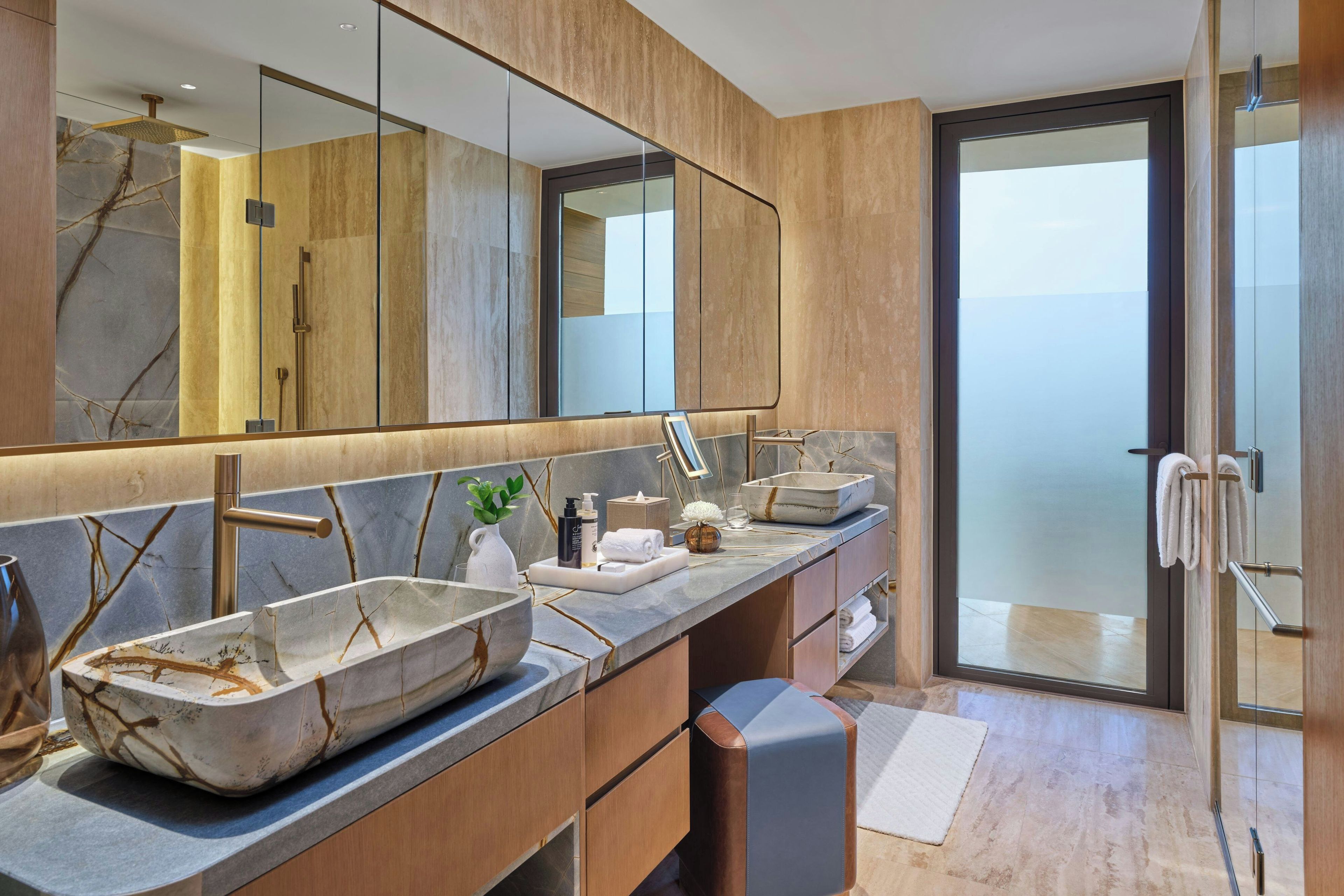 A modern bathroom with a large mirror, two sinks, a shower, and a glass door leading to a balcony.