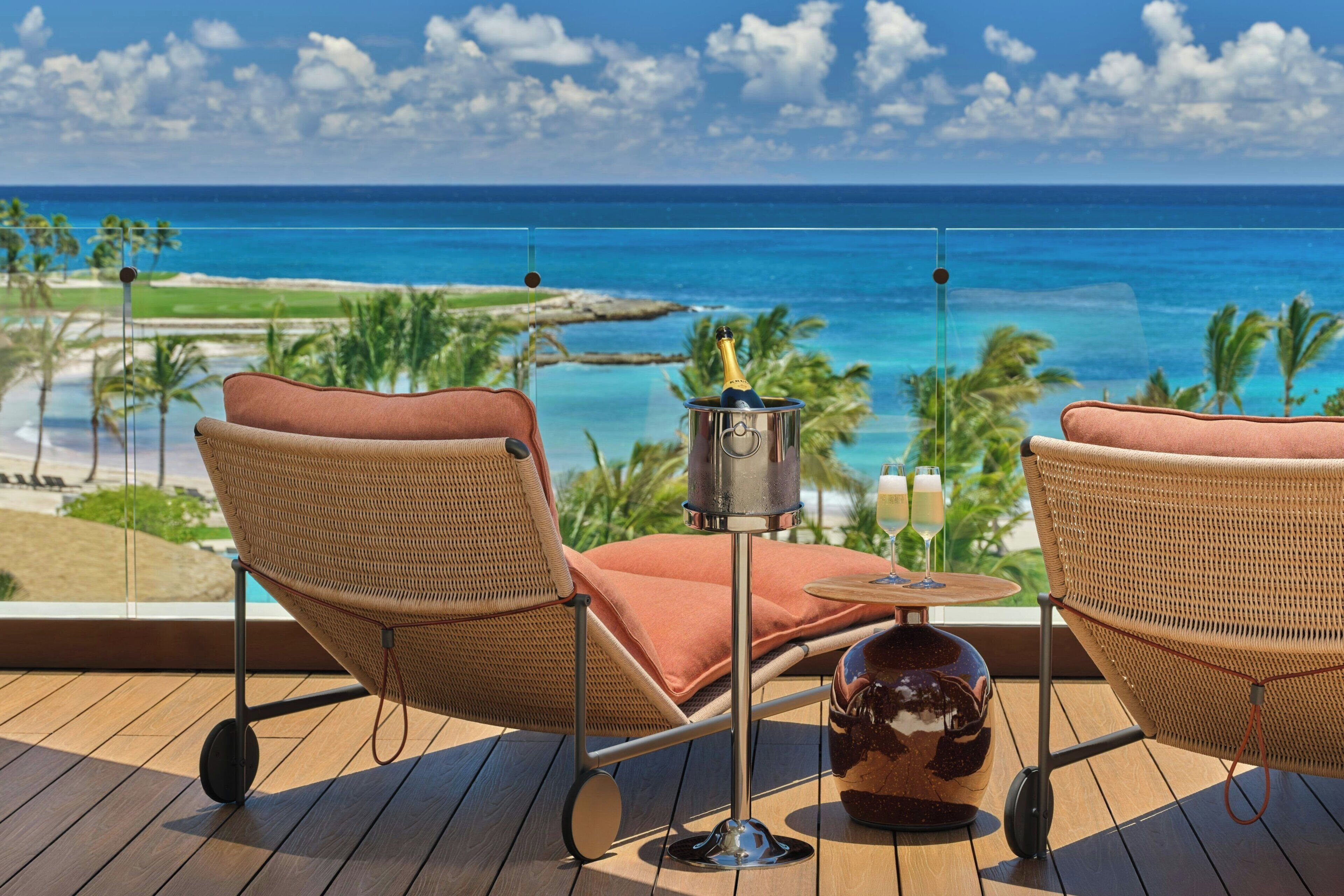 A balcony with wicker chairs, a small table, and a bottle of champagne.
