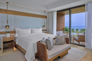 A modern bedroom with a large bed, a sofa, and a view of the ocean.