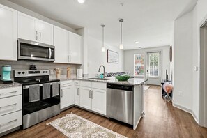 A modern kitchen with white cabinets, stainless steel appliances, and a central island. - Luxury 1BR Near NoDa & Uptown Charlotte (Charlotte)