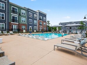 A pool area with lounge chairs, a swimming pool, and multi-story buildings with balconies. - Luxury 1BR Near NoDa & Uptown Charlotte (Charlotte)