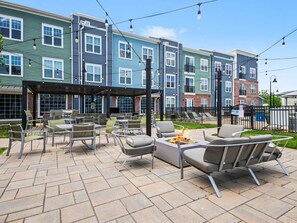 A patio with outdoor seating and a fire pit, surrounded by multi-story buildings with balconies. - Luxury 1BR Near NoDa & Uptown Charlotte (Charlotte)