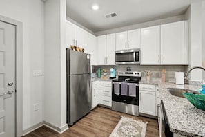A modern kitchen with white cabinets, stainless steel appliances, and a granite countertop. - Luxury 1BR Near NoDa & Uptown Charlotte (Charlotte)