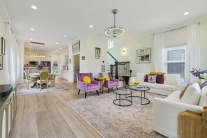 A spacious living room with a dining area, a staircase, and a kitchen in the background. - Spacious + Luxurious New Orleans Escape • Treat Yourself (New Orleans)