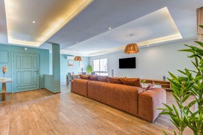 A modern living room with a large sofa, wooden flooring, a flat-screen TV, and a dining area with a table and chairs. - Mohammed VI | Elegant 3-bedroom apartment with a terrace (Maroc)