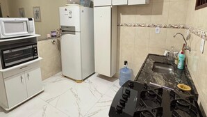 Een keuken met een gasfornuis, magnetron, koelkast en kastjes.