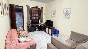 Een woonkamer met een bank, een televisie en een ventilator.