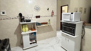 Een keuken met een magnetron, koffiezetapparaat en een kleine koelkast.