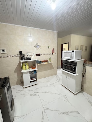 A kitchen with a microwave, coffee maker, and a small refrigerator. - Beautiful house near the beach. (Cabo Frio)