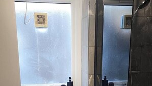 Ein Badezimmer mit Waschbecken, Fenster, Dusche und Tür.
