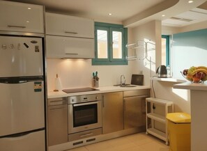Una cucina moderna con elettrodomestici in acciaio inossidabile, una finestra con persiane color acquamarina e un cestino giallo.