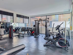 Ein modernes Fitnessstudio mit verschiedenen Trainingsgeräten, großen Fenstern und Blick auf die Stadt.