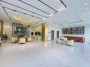 Eine großzügige Lobby mit einer Kandelaber, einer Sitzecke, einer Rezeption und Topfpflanzen.