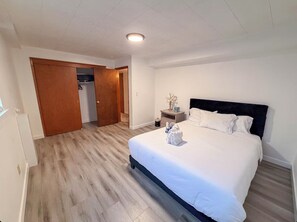 A hotel room with a bed, a nightstand, a wooden floor, a closet, and a ceiling light.