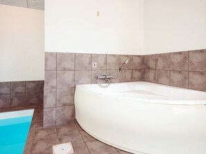 A bathroom with a bathtub, a shower, and a small pool area. - 5 Star Holiday Home in Hadsund (Hadsund)