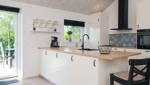 A modern kitchen with white cabinetry, a wooden countertop, a black faucet, and a built-in oven. - 5 Star Holiday Home in Hadsund (Hadsund)
