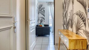 A hallway with a door, a sofa, and a wooden side table. - XAVIER – F2 cosy avec balcon à Rouen (Rouen)