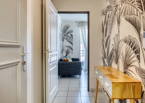 A hallway with a door, a sofa, and a wooden side table. - XAVIER – F2 cosy avec balcon à Rouen (Rouen)