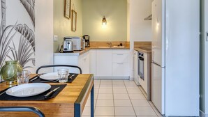A compact kitchen with white cabinets, a refrigerator, a coffee maker, and a toaster. - XAVIER – F2 cosy avec balcon à Rouen (Rouen)